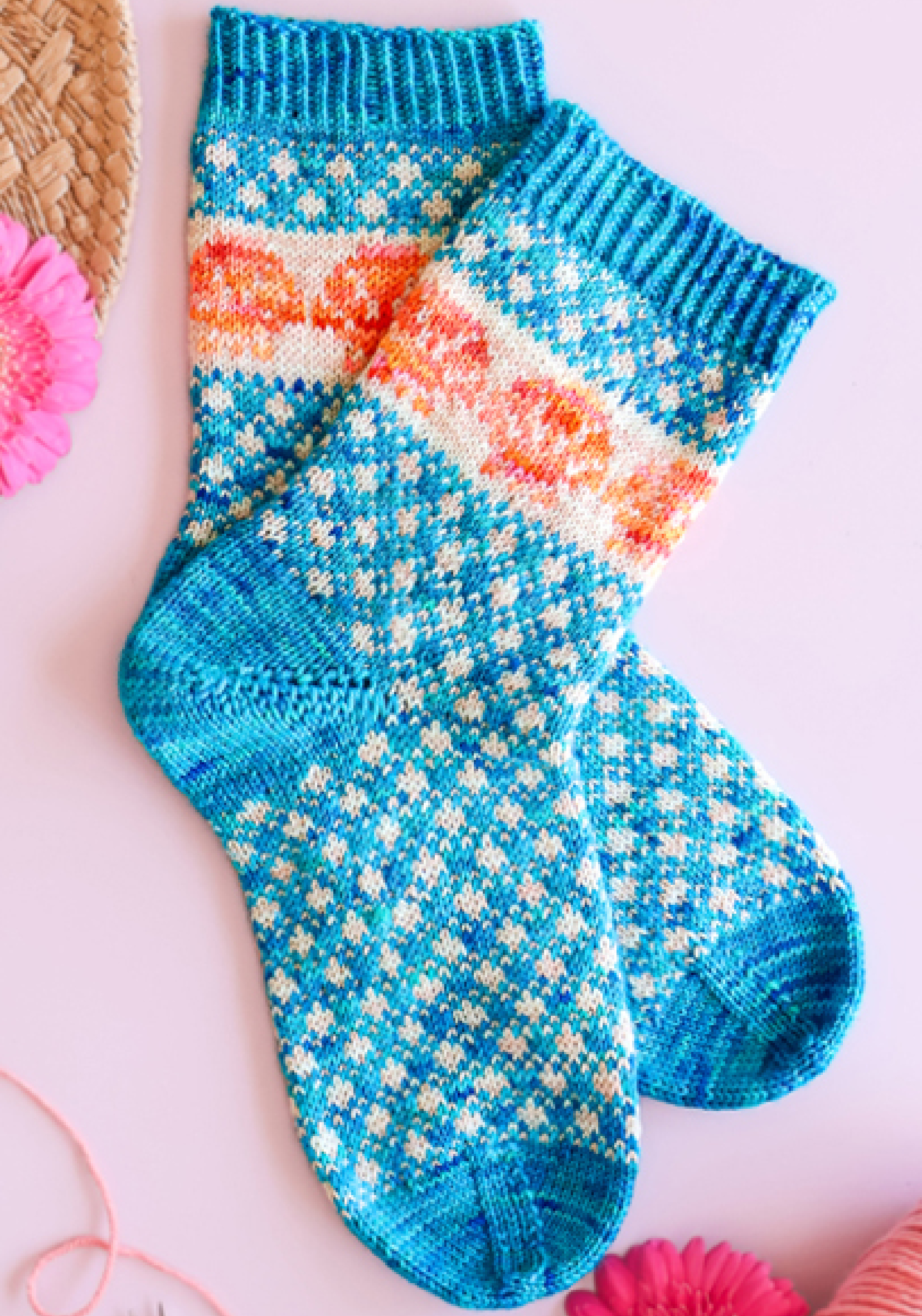 Chaussettes tricotées bleues à motifs jacquard colorés avec détails floraux orange et blancs, idéales pour tricot DIY, accessoires hiver handmade, mode cocooning et loisirs créatifs