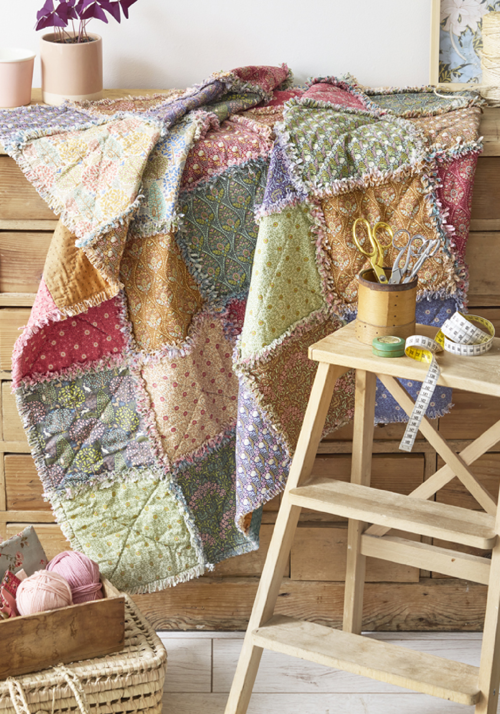 Plaid patchwork en tissus floraux et imprimés colorés avec finitions effilochées, ambiance atelier couture chaleureuse avec accessoires de mercerie, idéal pour quilting DIY, patchwork artisanal, décoration textile et loisirs créatifs couture