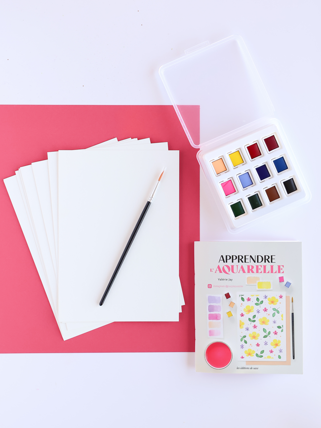 Kit pour apprendre l’aquarelle avec palette de peintures, pinceau, feuilles de papier aquarelle et livre explicatif proposant des exercices et créations colorées.