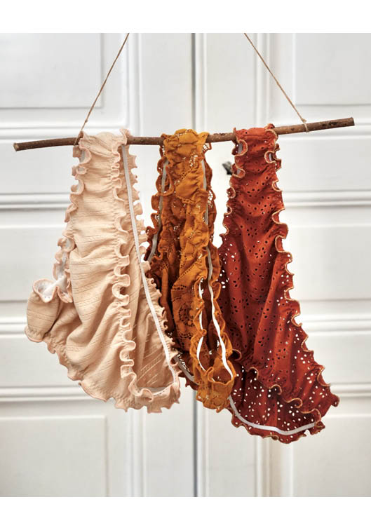 Volants en tissu brodé et froufrous suspendus sur branche en bois, nuances beige, ocre et terracotta, idéal pour couture DIY, création textile, mercerie créative et inspiration mode bohème artisanale
