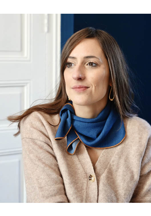 Portrait lifestyle d’une femme brune portant un cardigan beige et un foulard bleu élégant, style chic et intemporel, idéal pour mode féminine, accessoires tendance, portrait lifestyle et inspiration casual élégante
