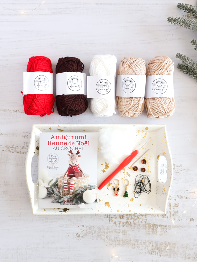 Kit amigurumi Renne de Noël au crochet avec pelotes de laine, crochet, accessoires et livret explicatif, présenté dans une ambiance festive de Noël.