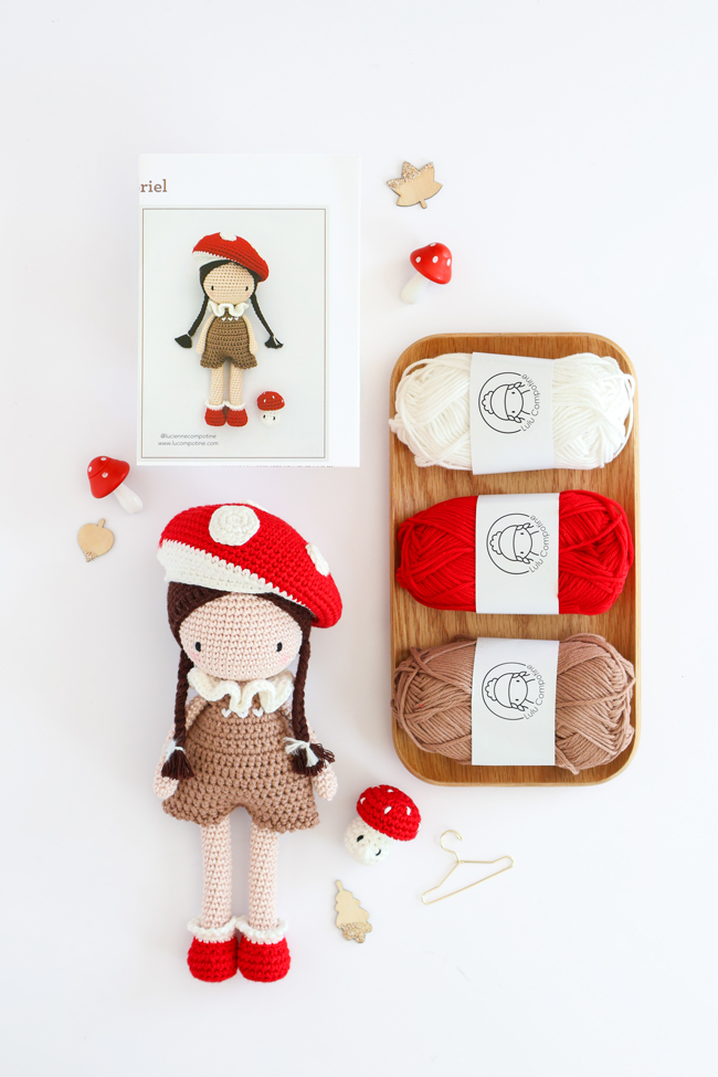 Contenu de la panoplie Lulu au pays des champignons de Sandra Muller (Lulu Compotine) : poupée au crochet avec tenue inspirée des champignons, pelotes de laine, accessoires et livret d'instructions sur fond blanc.