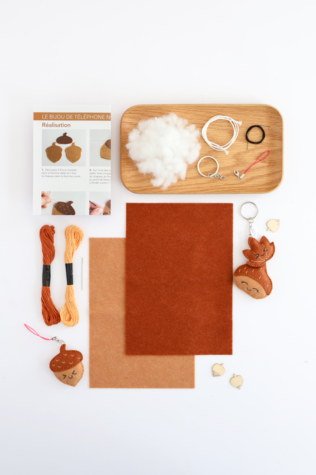 Contenu du kit de loisirs créatifs Bijou de téléphone Faon : feutrine, fils à broder, rembourrage, cordon, anneaux, accessoires de montage, tutoriel pas à pas et porte-clés faon, présenté sur fond blanc.