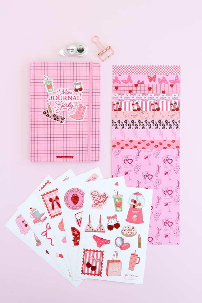 Contenu du coffret Mon Journal créatif : carnet de journaling, feuilles de papiers décoratifs, planches de stickers, ruban adhésif décoratif, roller de colle et pince à papier, présentés sur un fond rose pastel.