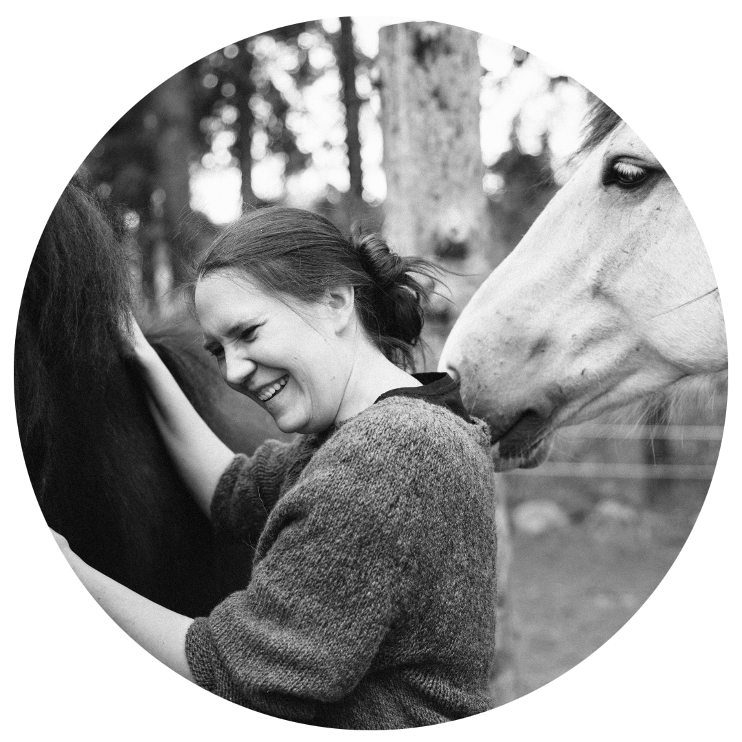 Portrait en noir et blanc d’une femme souriante au contact de chevaux en extérieur, ambiance naturelle et authentique, idéal pour portrait lifestyle, passion équestre, nature et photographie émotionnelle