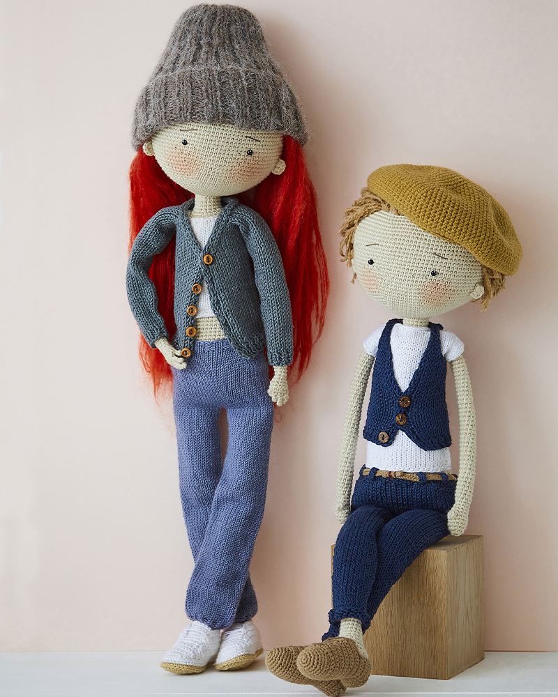 Deux poupées tricotées style amigurumi avec vêtements et accessoires en laine, l’une debout avec bonnet gris et cheveux rouges, l’autre assise avec béret beige, créations artisanales idéales pour tricot DIY, décoration handmade et univers kawaii textile