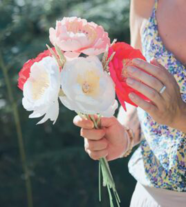 Main tenant un bouquet de fleurs colorées (pivoines et renoncules) en extérieur, ambiance printanière et romantique, idéale pour décoration florale, mariage, DIY fleurs et inspiration lifestyle naturelle