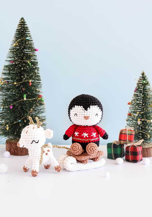 Personnages amigurumi crochetés sur le thème de Noël avec pingouin en pull rouge et petit renne, décor festif avec sapins et cadeaux, idéal pour crochet DIY, décoration de Noël, loisirs créatifs et créations faites main kawaii
