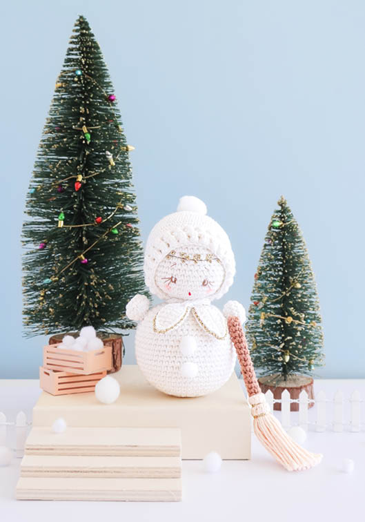 Bonhomme de neige amigurumi crocheté avec bonnet blanc et écharpe rayée, décor de Noël miniature avec sapins enneigés, idéal pour crochet DIY, décoration festive, loisirs créatifs et créations faites main kawaii