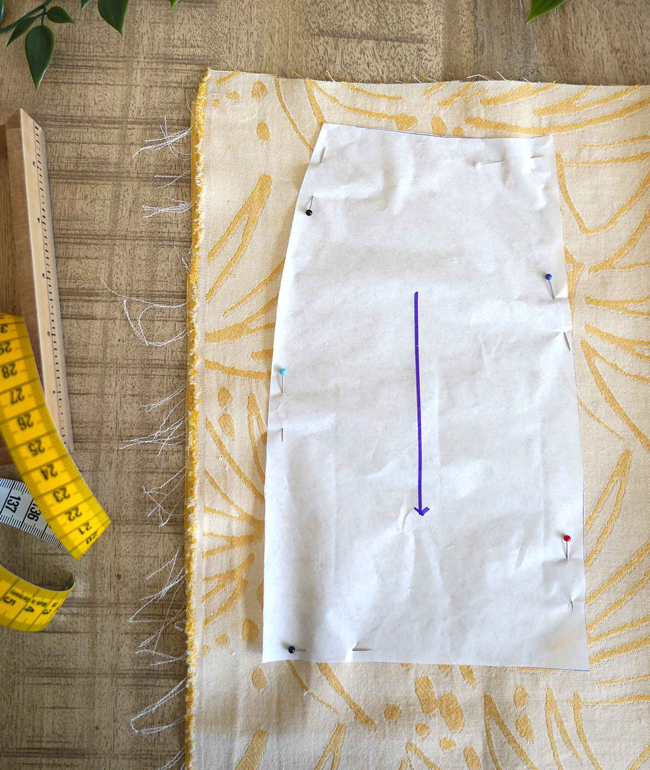 Patron de couture épinglé sur tissu imprimé avec mètre ruban et règle en bois, étape de préparation couture DIY idéale pour confection textile, création de vêtements et loisirs créatifs couture