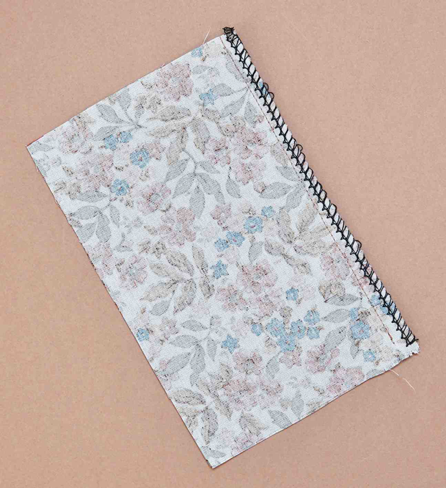 Échantillon de tissu fleuri avec couture surjet visible sur le bord, technique de finition textile idéale pour couture DIY, apprentissage couture, confection de vêtements et loisirs créatifs textiles