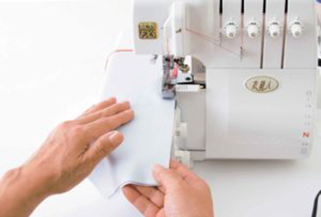 Surjeteuse en action réalisant la finition des bords d’un tissu, étape essentielle pour surfiler, assembler et obtenir des coutures propres et résistantes, idéale pour couture DIY, confection de vêtements et techniques de mercerie.