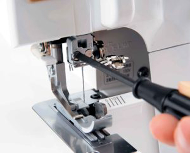 Entretien d’une machine à coudre avec tournevis de réglage, étape essentielle pour la maintenance, le nettoyage et le bon fonctionnement de la machine lors des projets de couture DIY.